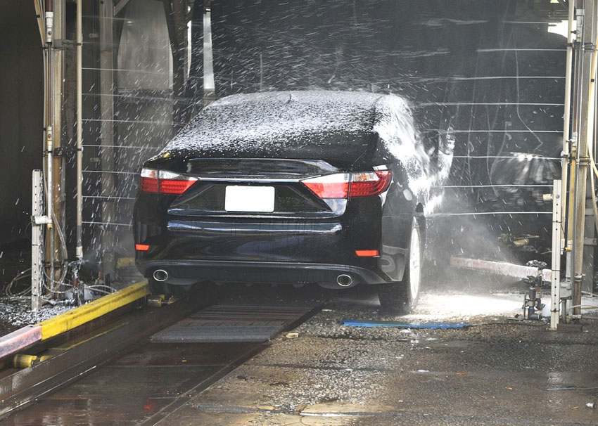 Black car being washed through an eco-friendly car wash system