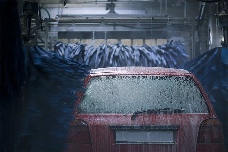 a red car driving through a car wash.