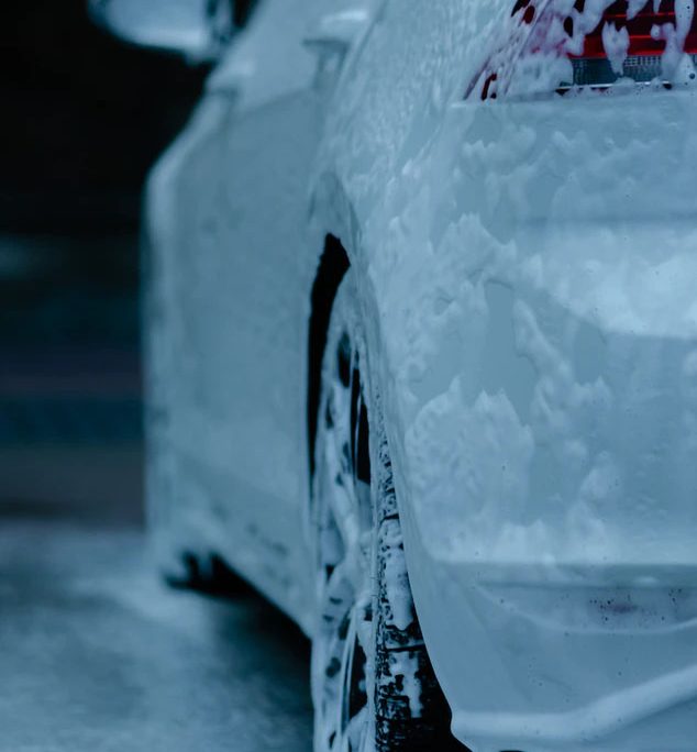 a white car covered in soap bubbles in a car wash
