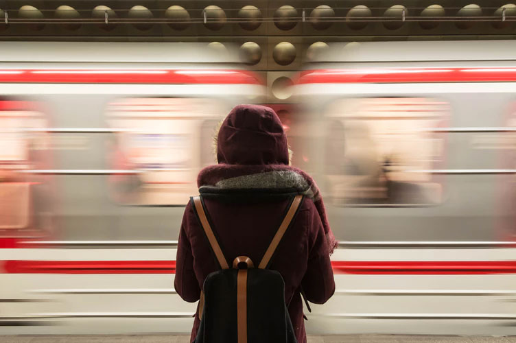 Woman stands on a platform with a speeding subway train in front of her