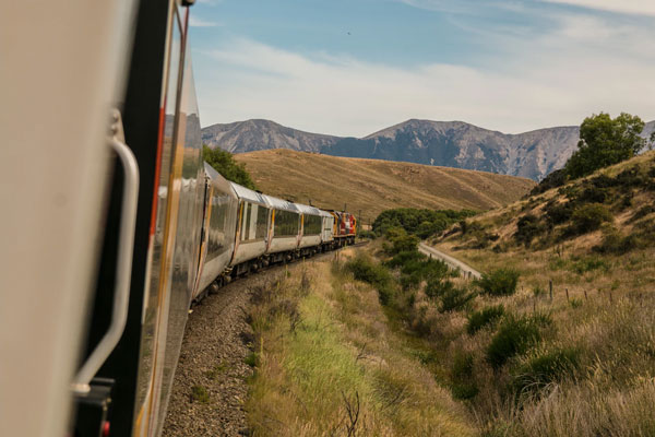 A train travels through a grassy plain land.