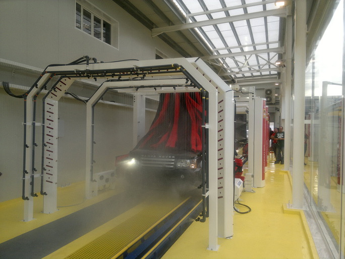 Black car goes through a conveyor car wash.