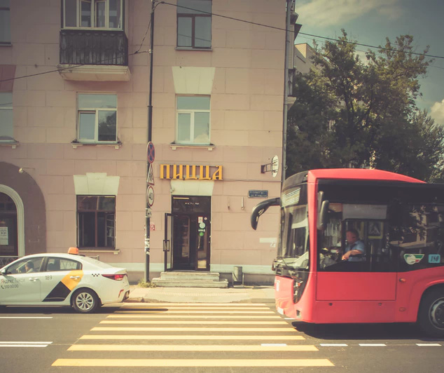 Red city bus drives through an intersection.