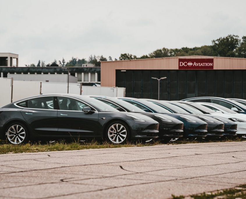 Black rental cars parked in a line in a rental car lot.